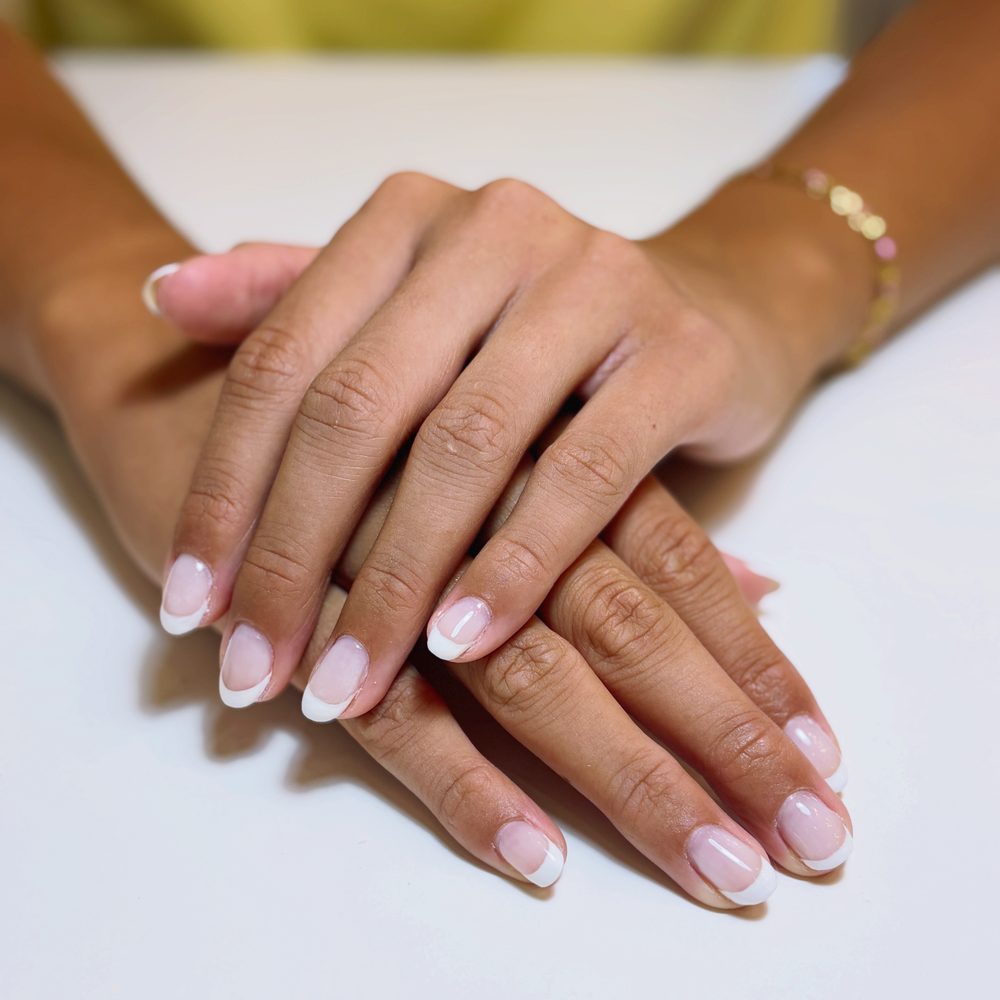 A soft natural French tip on short, rounded nails.