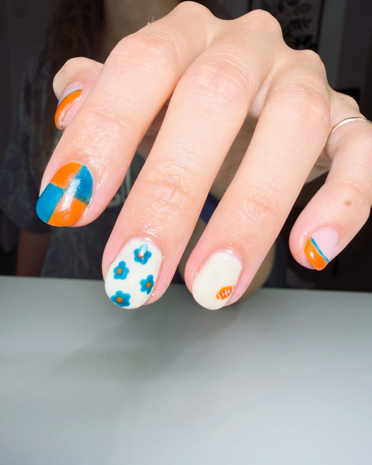 Hand-painted blue daisies and orange-and-teal color blocking.